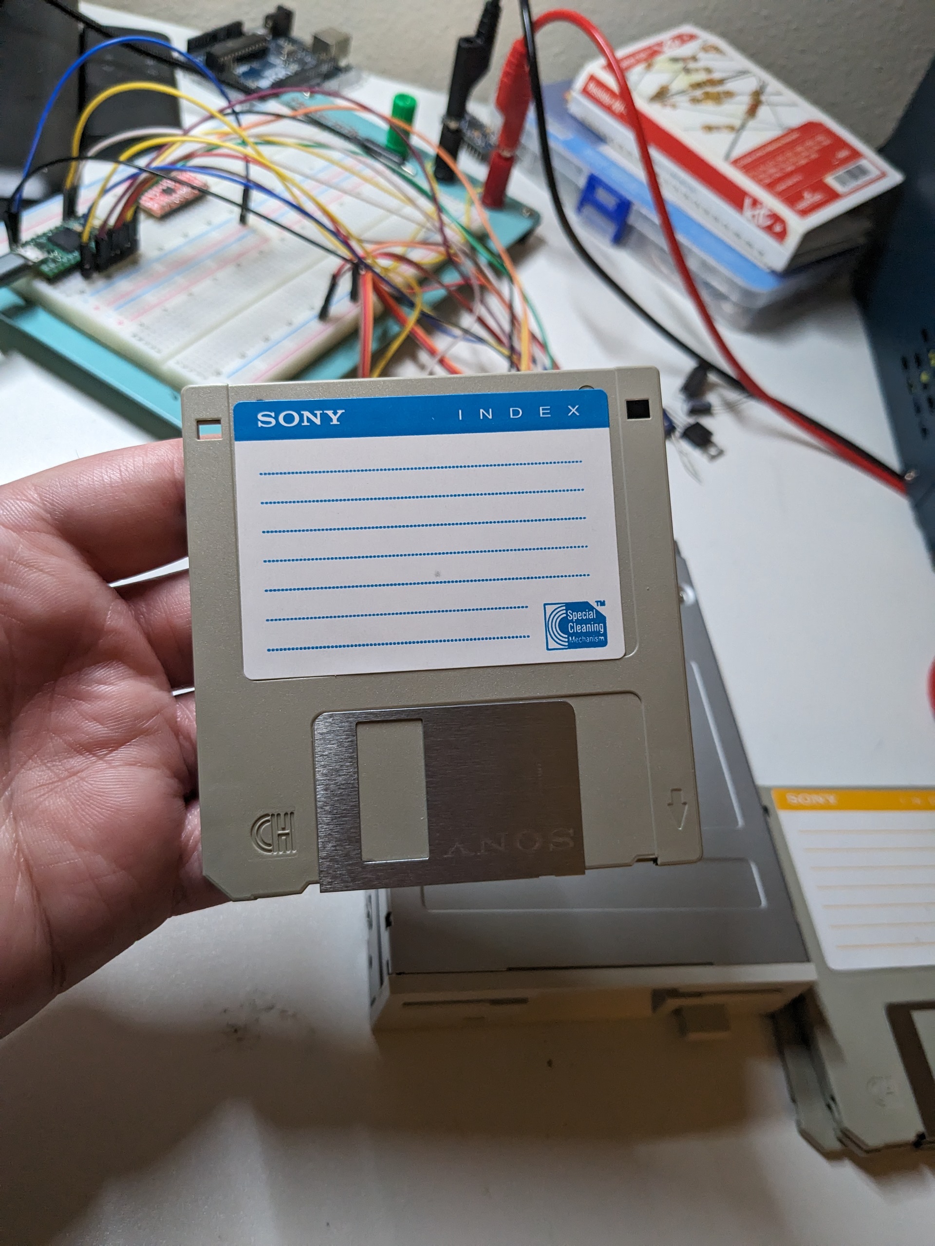 A blue floppy disk being held over a floppy drive